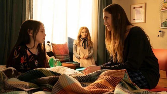 M3GAN sentada al fondo, tan inocente, mientras su creadora,
 Gemma (Allison Williams), a la derecha, 
y su sobrina, Cady (Violet McGraw) hablan tranquilamente